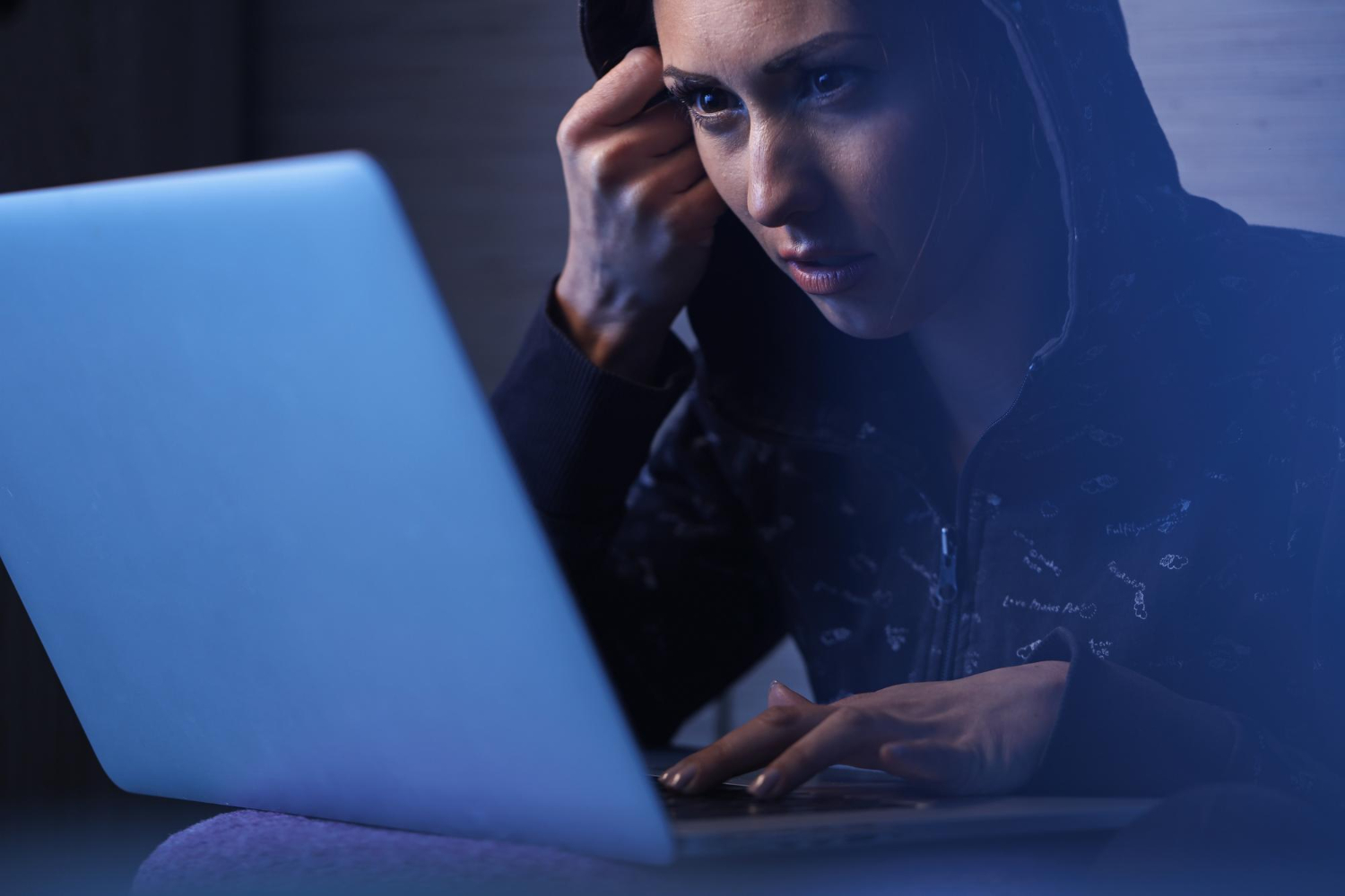 girl in hoodie using laptop